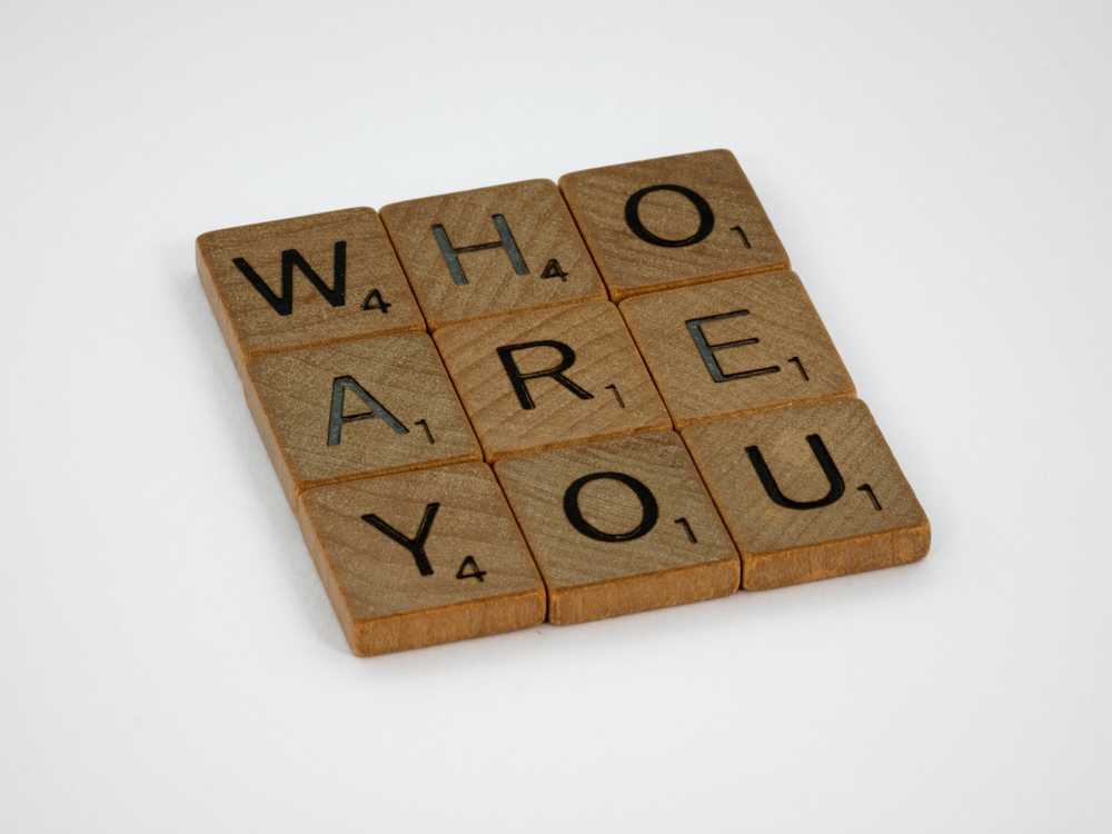 Brown wooden puzzle game board building words 'who are you'